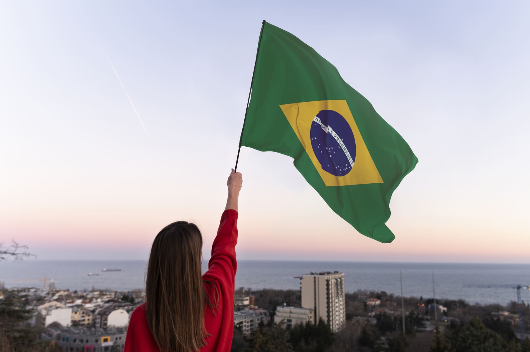 Bandeira do Brasil hasteada no Congresso Nacional em Brasília ao entardecer, representando o impacto das eleições presidenciais de 2026 no mercado de ações e na economia brasileira