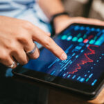 Pessoa analisando gráficos do mercado financeiro e investimentos em ETF em um tablet