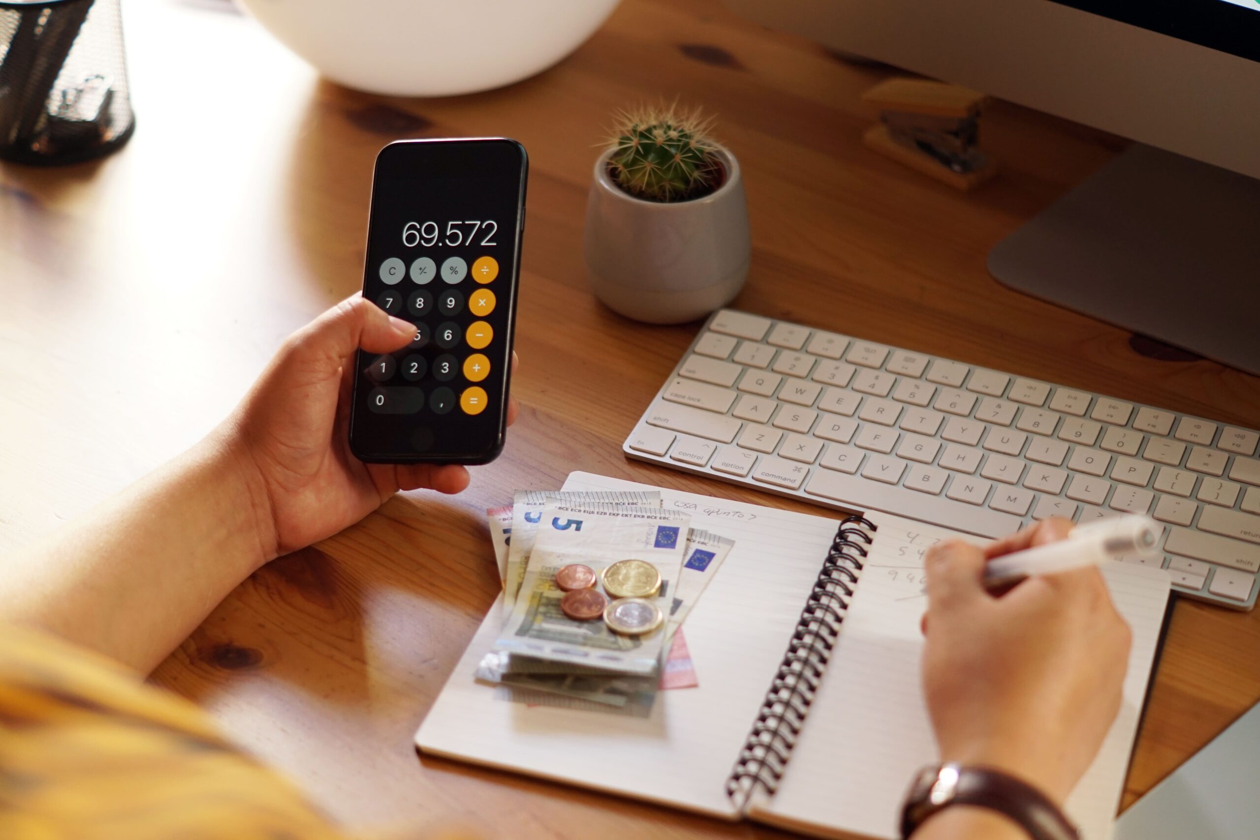 Pessoa calculando rendimentos e planejando onde investir com a Selic atual em mesa com dinheiro e calculadora